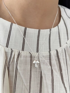 Close-up of minimalist 925 sterling silver mushroom pendant necklace on model
