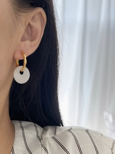 Detail of bamboo joint earrings featuring white agate stone on a female model