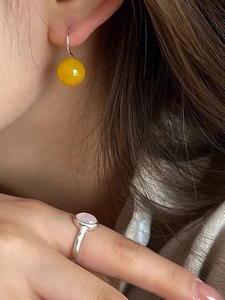 Detailed view of yellow agate bead earrings and pink gemstone ring on a female model