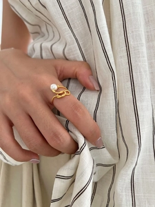 Detail of a 925 silver knotted gold ring with a single white pearl on a model's finger