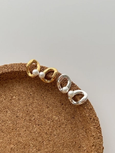 Detail of twisted metal hoop earrings with freshwater pearls in gold and silver finish