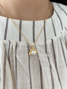 Nahaufnahme einer goldenen Perlenhalskette im geometrischen Stil auf gestreiftem Stoff