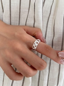Detailed view of S925 sterling silver ring with hollow woven heart pattern on finger