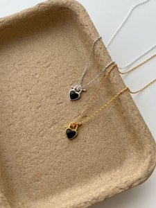Close-up of heart-shaped black agate pendants with gold and silver chain on organic tray