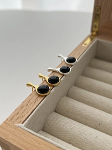Close-up of black onyx stud earrings in drop shape with gold and silver metal bases