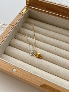 Detail of silver and gold mushroom necklaces on white jewelry box interior