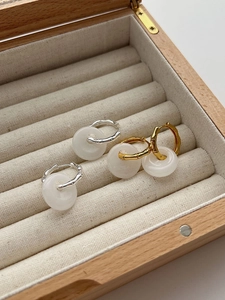 Detailed view of gold and silver bamboo earrings with white agate donut pendants