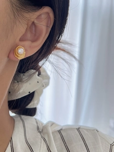 Gros plan d'une boucle d'oreille hexagonale dorée avec perle au style vintage