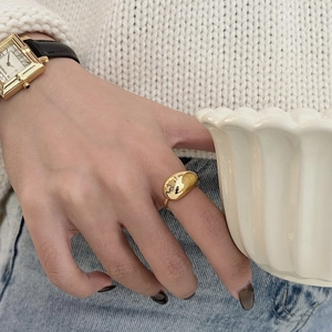 Polished gold bean shape ring for women on finger with cozy casual outfit scene