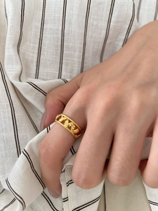 Close-up of a gold-toned chain texture ring on finger with elegant twisted edges