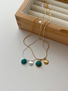 Detail of minimalist 925 sterling silver turquoise pendants on delicate gold and silver snake chains