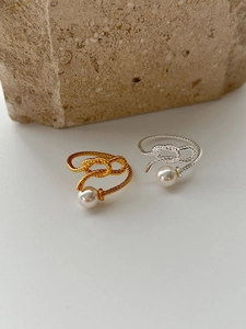 Close-up of gold and silver woven knot rings featuring lustrous round white pearls