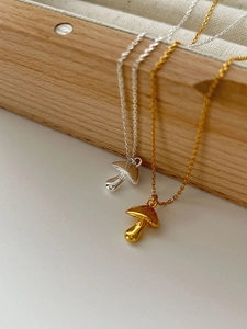 Detailed close-up of gold and silver mushroom pendants on delicate 925 sterling silver chains
