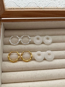 Detailed flat lay of bamboo texture silver hoops and white agate donut pendants in a jewelry box