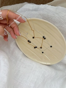 Détail de colliers en argent 925 avec pendentifs cœur noir sur un plateau céramique