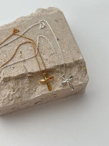Detail of twisted cross pendants in gold and silver finish on textured stone base