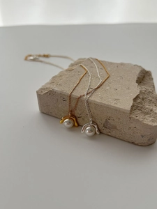 Detail von geometrischen Perlenanhängern in Gold und Silber auf Natursteinsockel