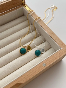 Detailed shot of minimalist 925 silver and gold necklaces with turquoise pendants in a box