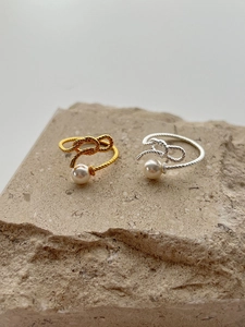 Detail of twisted silver and gold knot rings with elegant white pearls on stone