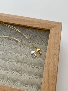 Close-up of mushroom pendant necklaces in gold and silver on vintage glass background