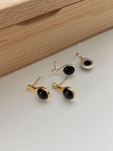 Macro shot of minimalist teardrop earrings featuring gold silver plating and black onyx stones