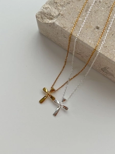 Detailed close-up of gold and silver twisted cross pendants on minimalist stone background