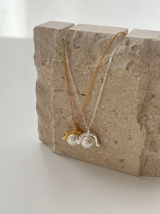 Detail von minimalistischen Gold- und Silberperlenketten auf einem strukturierten Stein