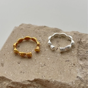 Minimalist twisted silver and gold open rings set displayed on natural stone texture