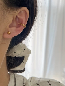 Detail von hochglänzendem goldenem Ear Cuff und Blumen-Ohrstecker Set am Ohr