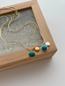 Detail of gold and silver necklaces featuring turquoise beads and metal round pendants