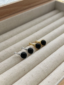 Close-up of minimalist silver and gold drop earrings with black agate inlays