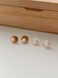 Détail de boucles d'oreilles lotus géométriques en or et argent avec des perles