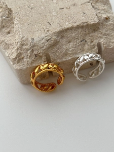Macro view of interwoven S925 sterling silver and gold plated open rings on stone base