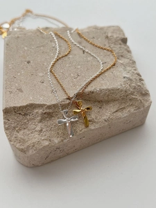 Detail view of twisted s925 silver and gold cross pendants on a natural stone background