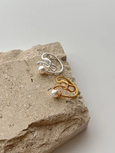 Macro detail of silver and gold knotted rings with round white pearls on a stone