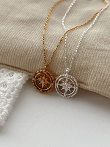 Detail of starburst compass pendants with zircon in gold and silver finish