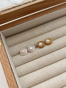 Gros plan de boucles d'oreilles perles lotus géométriques en finitions or et argent