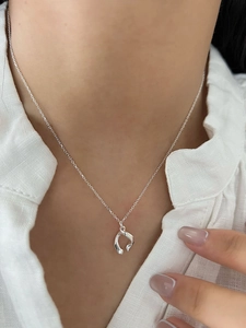 Polished silver irregular pendant necklace styled on model with a white linen shirt