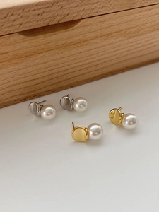 Detailed view of elegant silver and gold irregular metal studs with lustrous white pearls