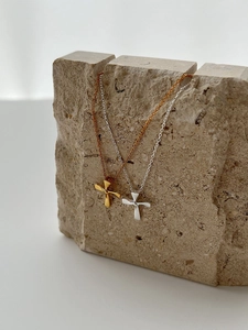 Detail of minimalist knotted cross pendants in polished gold and silver finishes