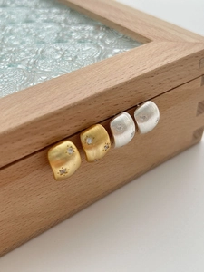 Dettaglio di orecchini a C opachi in argento e oro con zirconi e stella su legno
