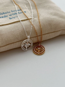 Detailed view of silver and gold hexagram compass pendants with sparkling crystals