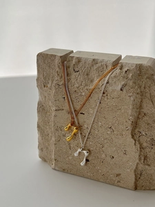 Detail of molten lava pendant necklace in gold and silver finish on stone display