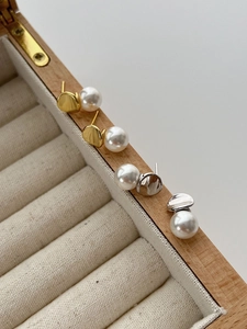 Detail of irregular metal disk earrings with round white pearls in gold and silver finish