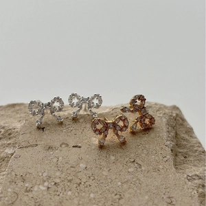 Luxury sparkling rhinestone bow stud earrings in silver and gold finishes on stone base