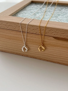 Polished silver and gold abstract horseshoe pendant necklaces on wooden jewelry box
