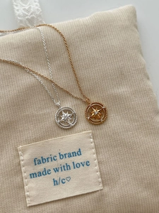 Detail of silver and gold hexagram star necklaces with zircons on a beige velvet bag