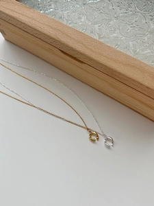 Close-up of irregular circular pendants in gold and silver finish with fine chain