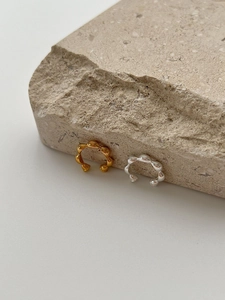 Detailaufnahme goldener und silberner Earcuffs auf natürlichem Stein mit Textur-Hintergrund