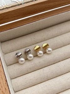 Macro shot of white pearl earrings with gold and silver bases in a jewelry box